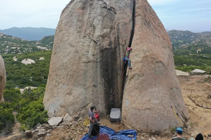 A youth climbs a granite boulder on belay at Freedom Land - Camp Care More adventure sports