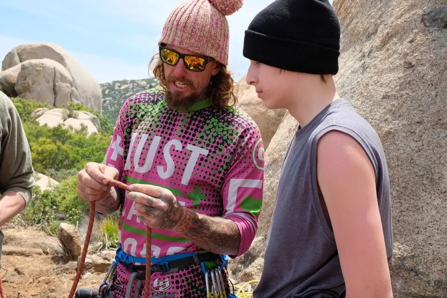 Jamie Leibert teaching a youth rope technique at the base of granite boulders at Freedom Land camp